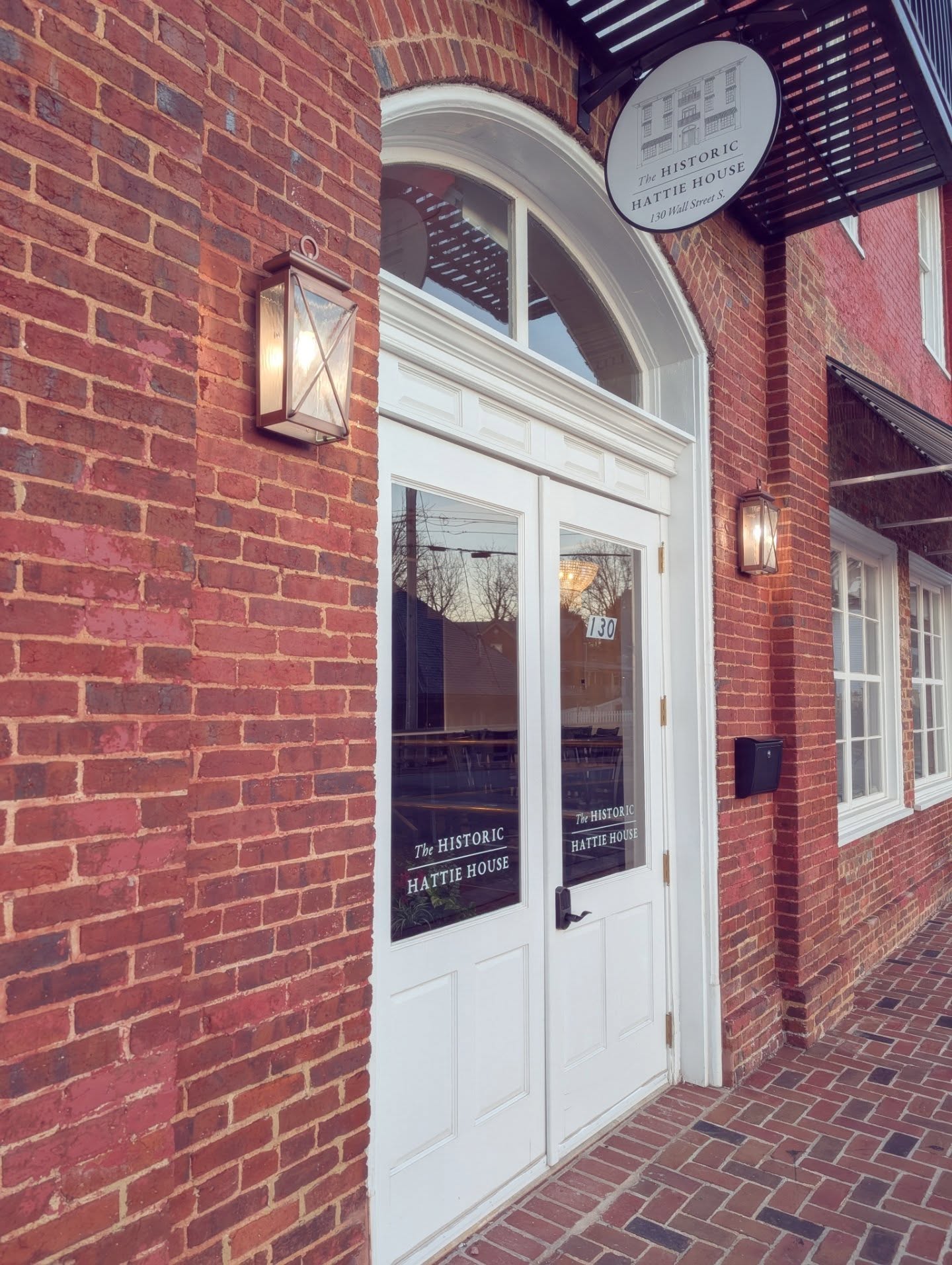 Brick entrance to The Historic Hattie House beneath its hanging sign