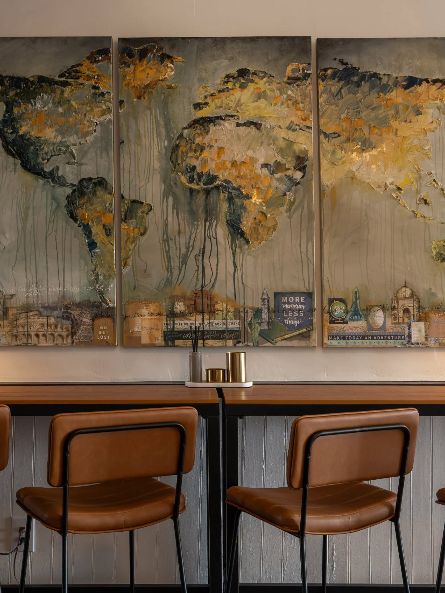 Large mixed-media world map artwork above leather bar chairs
