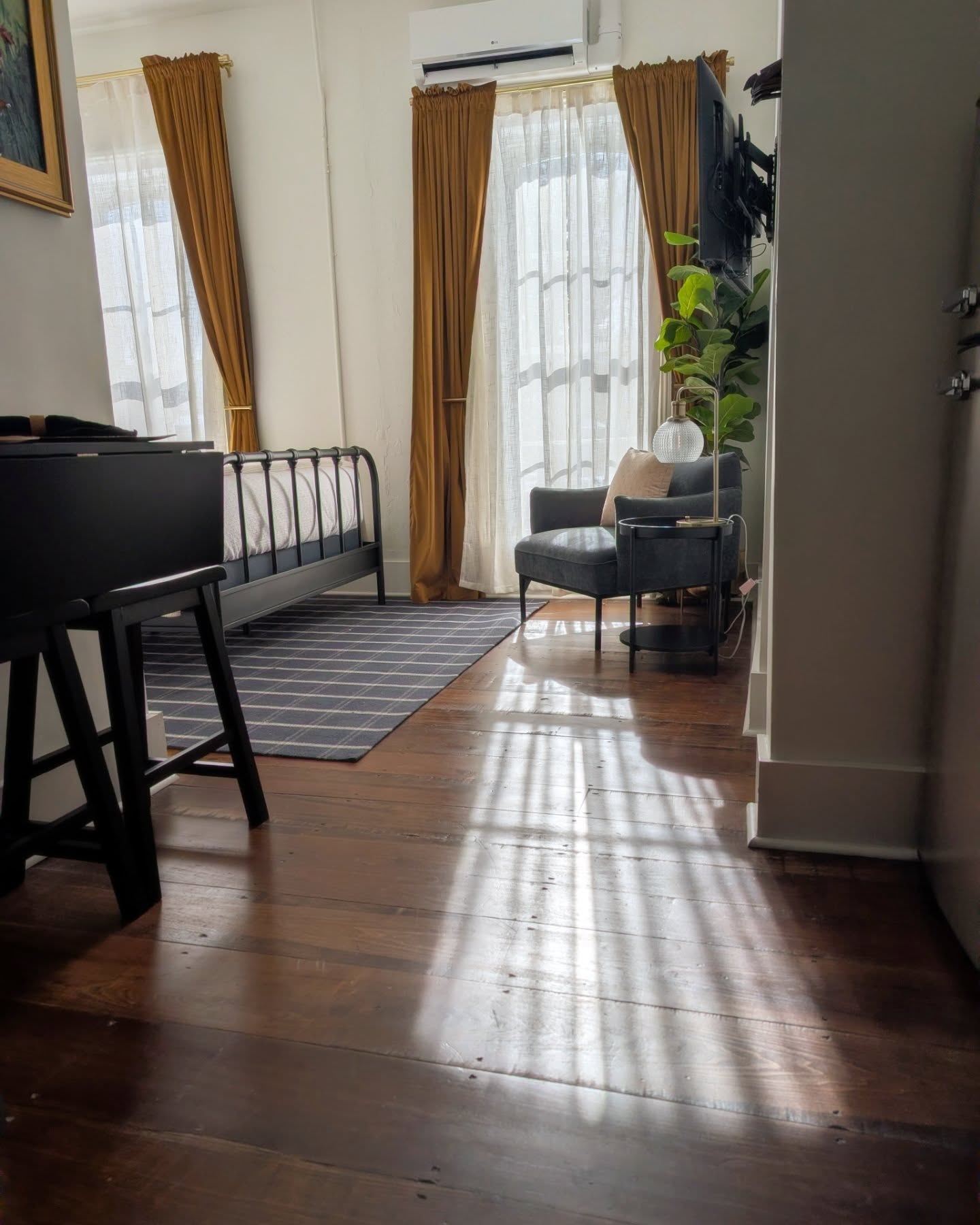 Suite sitting area with iron daybed, reading chair, tall windows, and original wood floors